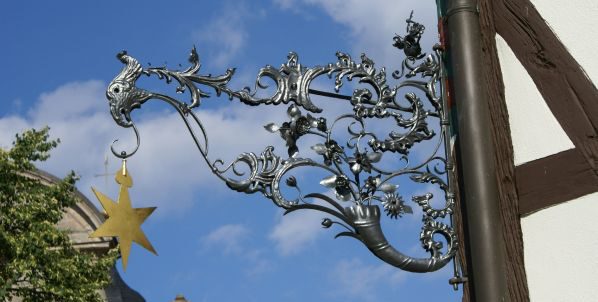 Das historische schmiedeeiserne Gasthausschild mit goldenem Stern vor blauem Himmel